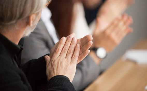 Senior gray-haired businessman clapping hands attending conference